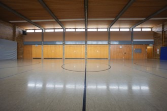 Large sports hall with wooden elements and a central playing field marker, Schlehengäu Grund Schule