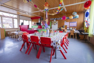 Bright kindergarten room with colorful decorations and red furniture creates a festive atmosphere,