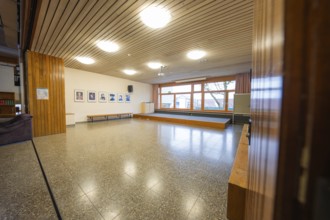 Another common room with parquet floors, wooden walls and large windows, decorated with picture
