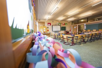 Paper chains hanging in a classroom with a view of windows and rows of seats, Schlehengäu Grund