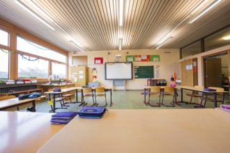 Empty classroom with a view of seating arrangements and blackboards, well-lit through large