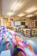 Classroom with colorful paper chains and blackboards, equipped with wooden school desks,