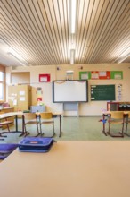 Classroom with wooden furniture and blackboard under an illuminated wooden ceiling, Schlehengäu