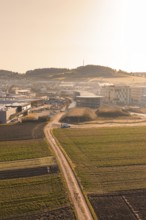 Rural road leads to large buildings in morning light over fields, new hospital at Calw health