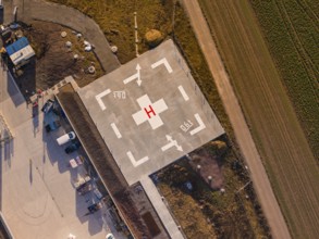 Concrete close-up of a helicopter landing pad with labels and adjacent fields, new hospital at the