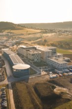 Modern buildings in an industrial area surrounded by fields at sunset, new hospital at Calw Health