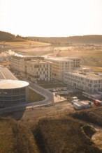 Modern architecture in rural surroundings with small fields and rolling hills, new hospital at the