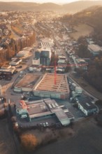 Aerial view of an urban building area with orange sky light and surrounding roads, Neubau Rewe,