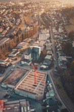 City view with construction crane in the midst of buildings and roads in the setting sun, Neubau