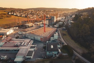 Urban scene with construction crane surrounded by residential areas and rolling hills at dusk,