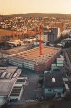Industrial area with crane and new buildings in sunset light, on the edge of a city in a hilly