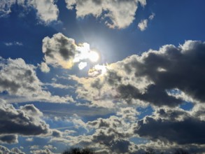 Looking at the sun behind clouds Cumulus fractus against a blue sky, international