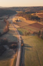 A country road winding through fields and hills in warm sunlight, Aidlingen, Böblingen District,