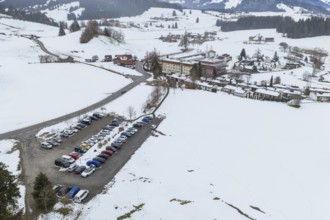 Parking lot full of cars in a snowy, hilly winter landscape from above, specialist clinic for
