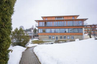 Modern building in snowy landscape with clear skies and surrounding trees, specialist clinic for