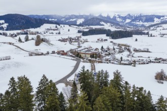 Wide view of snowy village in mountainous winter landscape with clouds in the sky, specialist