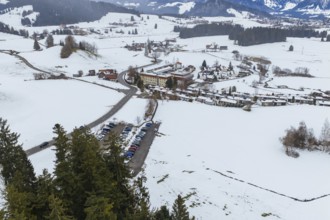 Snow-covered winter landscape with a village, forest trail and fields in the foreground, specialist