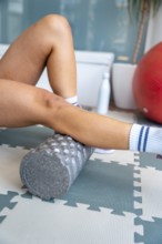 Person's legs performing self myofascial release actively with a foam roller, focusing on muscle
