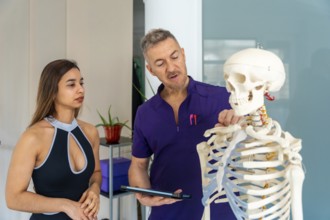 Experienced osteopath or physiotherapist showing a female patient spinal anatomy on a human