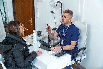 Doctor in scrubs having a conversation with a female patient during a medical consultation at a