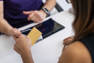 Patient paying medical bill with a credit card at a clinic reception, completing a healthcare
