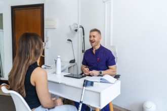 Experienced male physiotherapist in purple uniform consulting young female patient in modern clinic