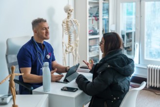Doctor in blue scrubs and stethoscope consulting a female patient regarding her health concerns,