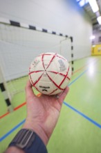 A hand holding a handball in front of a goal in a sports hall, Handball, Calw, Germany