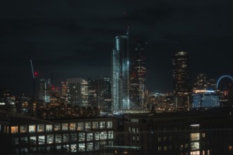 Illuminated skyline of London at night with modern skyscrapers in the foreground, London, United