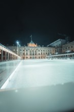 Large empty ice rink in front of an illuminated building at night, London, United Kingdom