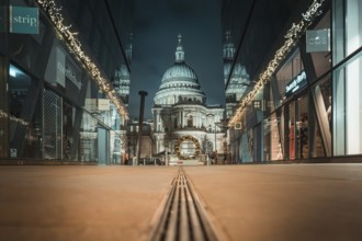 View of an illuminated cathedral between two modern buildings at night, London, Great Britain