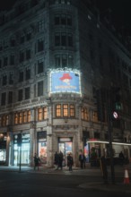 Illuminated theatre building at night with advertisement for a performance, London, Great Britain