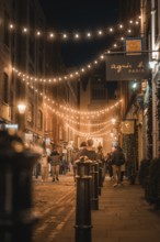 Evening street scene with fairy lights and people strolling in a city, London, Great Britain