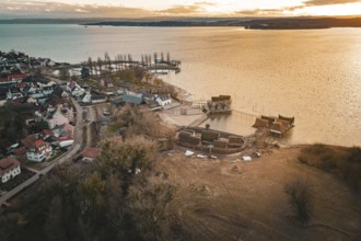 Panorama of a village with stilt houses on the lakeside at sunset, captured in warm light, stilt