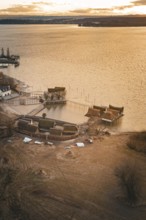 Historic stilt houses on the shore of a lake at sunset with warm light and peaceful atmosphere,