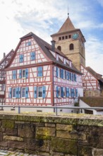Half-timbered building and church tower with clock and blue shutters, traditional ambiance,
