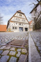 Half-timbered house with cobblestone street and wooden fence in a historic setting, Ötisheim,