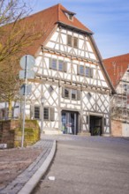 Timbered house with red roof and road signs against a blue sky, Ötisheim, Enzkreis, Germany