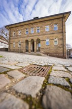 Historic building with arches and stone path under partly cloudy sky, Ötisheim, Enzkreis, Germany