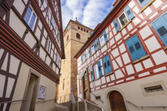 Historic half-timbered houses with blue shutters and tower view in a narrow lane, Ötisheim,