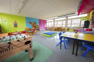 Cheerful playroom in kindergarten with table football, colorful walls and bright windows, homework