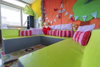 Cosy seating area with colorful pillows and cuddly toys, decorative background, homework