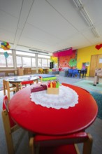 Creative environment in a kindergarten with round table and colored pencils, colorful decoration,