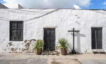 Typical white house with wooden doors and windows in an alley with volcanic crater at the back,