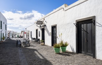 Typical white houses with colored doors and windows, alley with restaurant, Teguise, Lanzarote,
