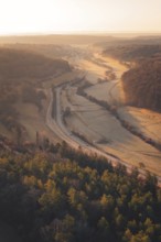 View of a valley with roads and forest in the soft light of the setting sun, quiet landscape,