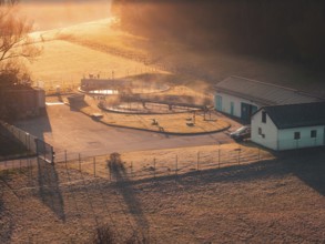 Sewage treatment plant in a meadow in soft sunlight, with fog and shade, quiet and idyllic,