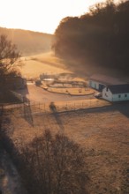 Sewage treatment plant at sunrise in a meadow with long shade, surrounded by trees and fog,