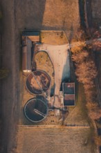 Top view of a sewage treatment plant with round basin surrounded by an autumnal landscape,