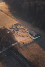 Sewage treatment plant surrounded by fields and trees, illuminated by the morning sun with long